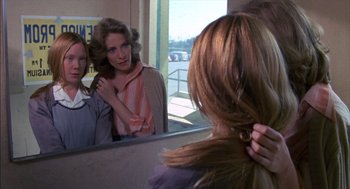 Movie still from “Carrie” (1976), directed by Brian De Palma – A woman looking in the mirror while holding her hair in front of a mirror; Close Up shot, Over the shoulder angle
