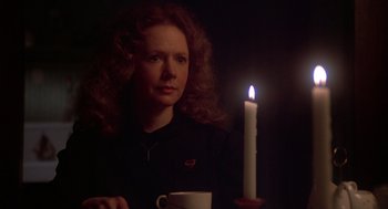 Movie still from “Carrie” (1976), directed by Brian De Palma – A woman holding a coffee cup in front of a candle; Close Up shot, Over the shoulder angle