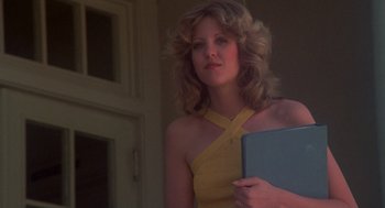 Movie still from “Carrie” (1976), directed by Brian De Palma – A woman in a yellow dress holding a blue laptop; Medium shot, Low angle