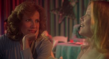Movie still from “Carrie” (1976), directed by Brian De Palma – A woman sitting at a table with another woman in the background; Close Up shot, Over the shoulder angle