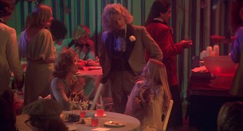 Movie still from “Carrie” (1976), directed by Brian De Palma – A group of people sitting around a table; Medium shot, Over the shoulder angle