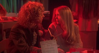 Movie still from “Carrie” (1976), directed by Brian De Palma – Two women sitting at a table talking to each other; Medium shot, Over the shoulder angle