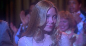 Movie still from “Carrie” (1976), directed by Brian De Palma – A woman with blonde hair is looking up at a crowd; Close Up shot, Over the shoulder angle