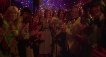 Movie still from “Carrie” (1976), directed by Brian De Palma – A group of people standing in a room clapping; Wide shot, High angle