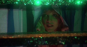 Movie still from “Carrie” (1976), directed by Brian De Palma – A woman peeking out from behind a green curtain; Close Up shot, Low angle