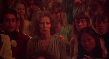 Movie still from “Carrie” (1976), directed by Brian De Palma – A group of people sitting in a room; Close Up shot, High angle
