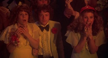 Movie still from “Carrie” (1976), directed by Brian De Palma – A group of young people standing around each other; Medium shot, Over the shoulder angle