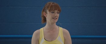 Movie still from “Carrie” (2013), directed by Kimberly Peirce – A woman with red hair wearing a yellow tank top; Close Up shot, Over the shoulder angle