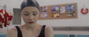 Movie still from “Carrie” (2013), directed by Kimberly Peirce – A woman in a black swimming cap and black top; Close Up shot, Over the shoulder angle