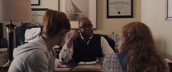 Movie still from “Carrie” (2013), directed by Kimberly Peirce – A man sitting at a table with three other people; Medium shot, Over the shoulder angle