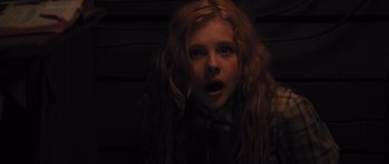 Movie still from “Carrie” (2013), directed by Kimberly Peirce – A girl with long red curly hair stares into the camera; Close Up shot, High angle
