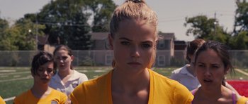 Movie still from “Carrie” (2013), directed by Kimberly Peirce – A woman in a yellow shirt is looking at the camera; Close Up shot, Over the shoulder angle