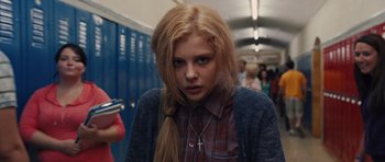 Movie still from “Carrie” (2013), directed by Kimberly Peirce – A woman with a cross necklace standing in a hallway; Medium shot, Low angle