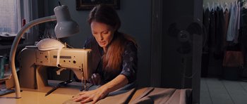 Movie still from “Carrie” (2013), directed by Kimberly Peirce – A woman using a sewing machine on a table; Medium shot, High angle
