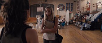 Movie still from “Carrie” (2013), directed by Kimberly Peirce – A woman standing in a room holding a bag; Medium shot, Over the shoulder angle