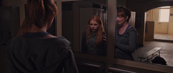 Movie still from “Carrie” (2013), directed by Kimberly Peirce – A woman standing in front of a mirror looking at herself in the mirror; Medium shot, Over the shoulder angle