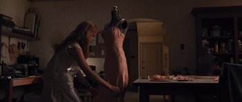 Movie still from “Carrie” (2013), directed by Kimberly Peirce – A woman in a white dress is working on a dress; Medium shot, Low angle