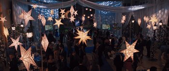 Movie still from “Carrie” (2013), directed by Kimberly Peirce – A group of people standing around a room with lights hanging from the ceiling; Extreme Wide shot, High angle