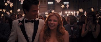 Movie still from “Carrie” (2013), directed by Kimberly Peirce – A young woman smiling at the camera while standing next to a young man; Close Up shot, Over the shoulder angle