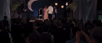 Movie still from “Carrie” (2013), directed by Kimberly Peirce – A group of people standing on a stage at a prom; Wide shot, Over the shoulder angle