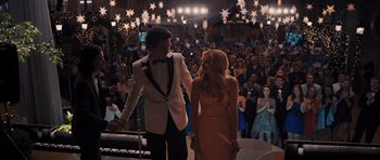 Movie still from “Carrie” (2013), directed by Kimberly Peirce – A man and a woman in formal wear walking in front of a crowd; Wide shot, Low angle