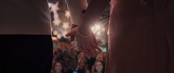 Movie still from “Carrie” (2013), directed by Kimberly Peirce – Two people holding hands in front of an audience; Extreme Close Up shot, High angle