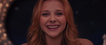 Movie still from “Carrie” (2013), directed by Kimberly Peirce – A person with long red hair smiling; Close Up shot, Low angle
