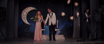 Movie still from “Carrie” (2013), directed by Kimberly Peirce – A man and a woman holding hands on a stage; Wide shot, Low angle