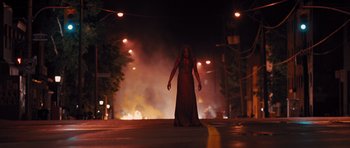 Movie still from “Carrie” (2013), directed by Kimberly Peirce – A woman in a red dress standing on the side of the street; Wide shot, Low angle