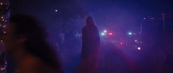 Movie still from “Carrie” (2013), directed by Kimberly Peirce – A person standing in the fog with a police car in the background; Wide shot, Low angle
