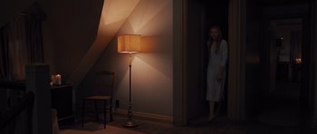 Movie still from “Carrie” (2013), directed by Kimberly Peirce – A woman standing in front of a lamp in a dark room; Wide shot, High angle