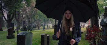 Movie still from “Carrie” (2013), directed by Kimberly Peirce – A woman holding an umbrella while standing in a cemetery; Medium shot, Over the shoulder angle