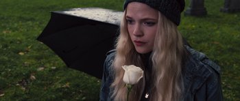 Movie still from “Carrie” (2013), directed by Kimberly Peirce – A woman holding a white rose while standing under an umbrella; Close Up shot, High angle