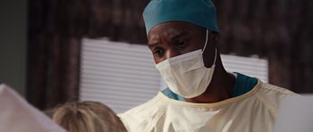 Movie still from “Carrie” (2013), directed by Kimberly Peirce – A doctor wearing a surgical mask and a surgical cap; Close Up shot, Over the shoulder angle