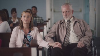 Movie still from “The Clovehitch Killer” (2018), directed by Duncan Skiles – A man and a woman sitting in a church pew; Medium shot, Low angle