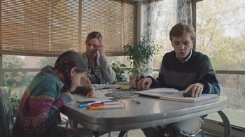 Movie still from “The Clovehitch Killer” (2018), directed by Duncan Skiles – Three people sitting at a table doing crafts; Medium shot, Low angle