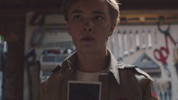 Movie still from “The Clovehitch Killer” (2018), directed by Duncan Skiles – A young man holding up a camera in a parking lot; Close Up shot, Low angle