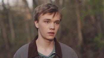 Movie still from “The Clovehitch Killer” (2018), directed by Duncan Skiles – A young man in a brown and gray jacket; Close Up shot, High angle