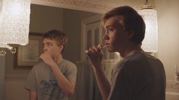 Movie still from “The Clovehitch Killer” (2018), directed by Duncan Skiles – Two young men brushing their teeth in front of a mirror; Close Up shot, Over the shoulder angle