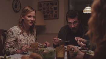 Movie still from “The Clovehitch Killer” (2018), directed by Duncan Skiles – A group of people sitting around a table eating food; Medium shot, Over the shoulder angle
