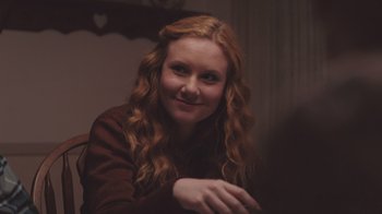 Movie still from “The Clovehitch Killer” (2018), directed by Duncan Skiles – A woman with long red curly hair sitting at a table; Close Up shot, Over the shoulder angle