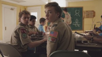 Movie still from “The Clovehitch Killer” (2018), directed by Duncan Skiles – A boy scout sitting in front of a group of other scouts; Medium shot, Over the shoulder angle