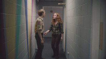 Movie still from “The Clovehitch Killer” (2018), directed by Duncan Skiles – A man and a woman are standing in a hallway; Medium shot, Over the shoulder angle