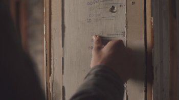 Movie still from “The Clovehitch Killer” (2018), directed by Duncan Skiles – A person is writing on a wall with a marker; Extreme Close Up shot, Overhead angle