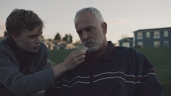 Movie still from “The Clovehitch Killer” (2018), directed by Duncan Skiles – An older man with a gray beard is being shaved by a woman; Close Up shot, Over the shoulder angle