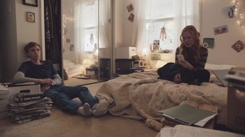 Movie still from “The Clovehitch Killer” (2018), directed by Duncan Skiles – Two people sitting on the floor in a room; Wide shot, High angle