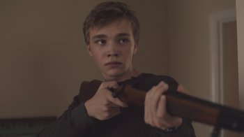 Movie still from “The Clovehitch Killer” (2018), directed by Duncan Skiles – A young man holding a gun in his hands; Close Up shot, Low angle