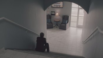 Movie still from “The Clovehitch Killer” (2018), directed by Duncan Skiles – A man sitting on the stairs of a building; Wide shot, High angle
