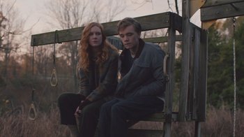 Movie still from “The Clovehitch Killer” (2018), directed by Duncan Skiles – A man and a woman sitting on a swing; Medium shot, Low angle