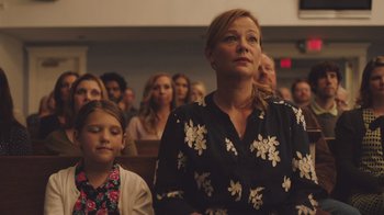 Movie still from “The Clovehitch Killer” (2018), directed by Duncan Skiles – A woman and a girl are sitting in the audience; Medium shot, Low angle